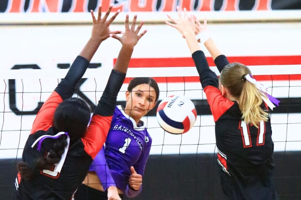 Gainesville's Jacey Carter-Mitchell (1) with a kill between The Rock's Arianna Howard (9) and Brianna Stevens (17). Photo by C.J. Gish