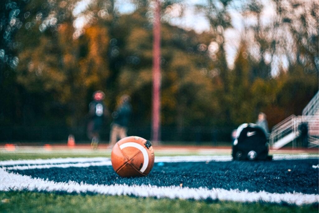 Football and helmet on field. Photo by Will-Colavito-unsplash