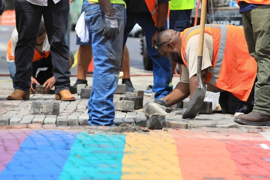 Gainesville Public Works employees work to remove bricks used in a rainbow crosswalk and replace them with unpainted bricks.