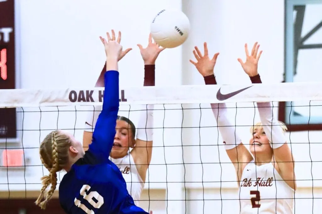 Oak Hall's Kendylle Bishop (14) and Lizzie Cannon (2) go for a block against Saint Francis Catholic's Hailey Schoster (16). Photo by C.J. Gish