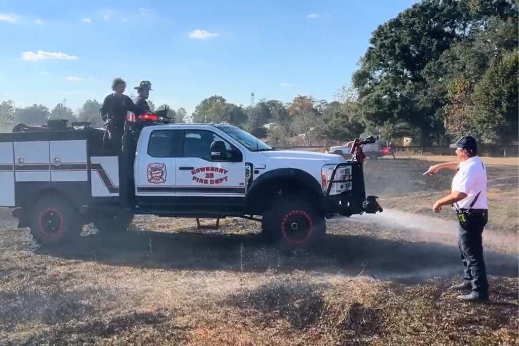 A Newberry Fire Department truck sprays the field after a brush fire.