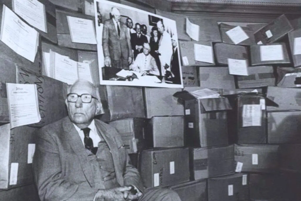 The photograph was likely taken on the 50th anniversary of the signing of Social Security in 1985. Behind Pepper is a photo of Franklin Roosevelt signing the legislation. Image Courtesy FSU Heritage & University Archives
