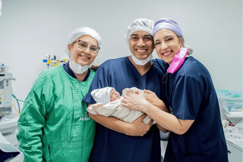 Three healthcare professionals holding a baby
