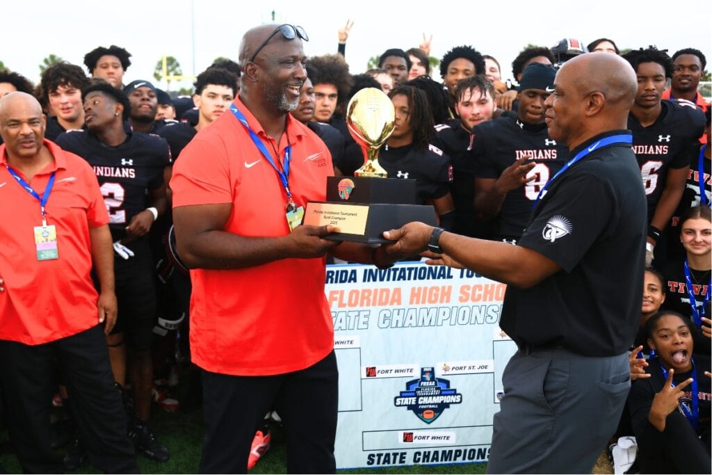 Fort White head coach Demetric Jackson (left) receives the trophy for a win against Port St. Joe in the Rural Florida Invitation Tournament Championship game. Photo by C.J. Gish