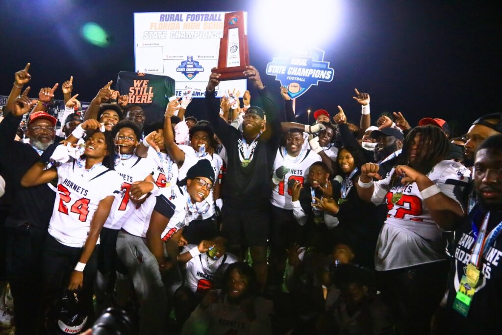 Hawthorne coach Cornelius Ingram raises the first-place trophy after the Hornets' win against Blountstown in the FHSAA Rural State Championship game. Photo by C.J. Gish