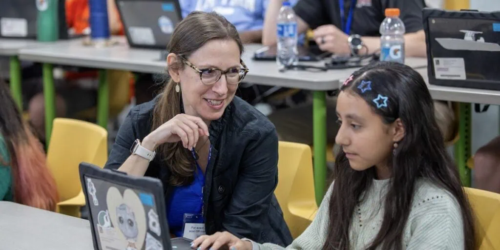 Teacher helps a student on the computer