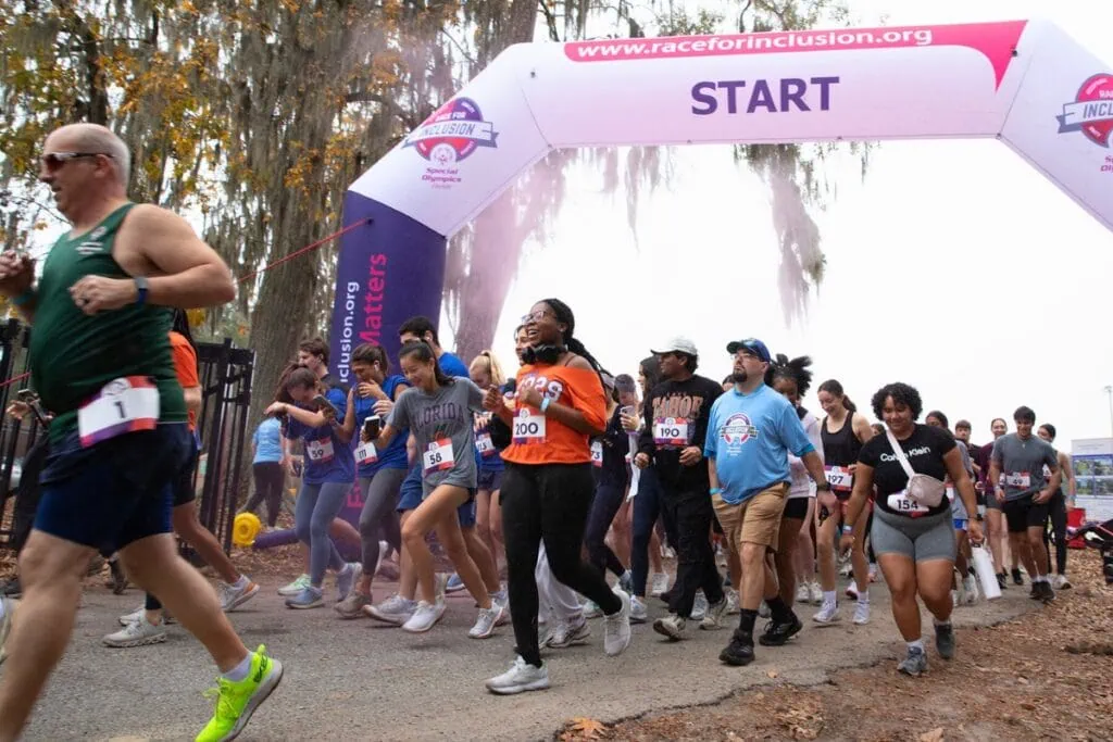 Surprised race participants duck and dust off pink-colored powder from a handheld race cannon.