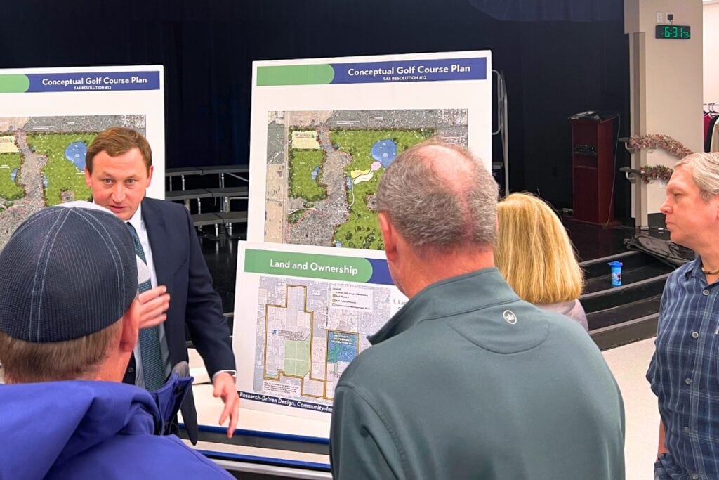 Tyler Matthews (suit) talks to residents about the proposed UF golf course project on Monday. Photo by Nick Anschultz