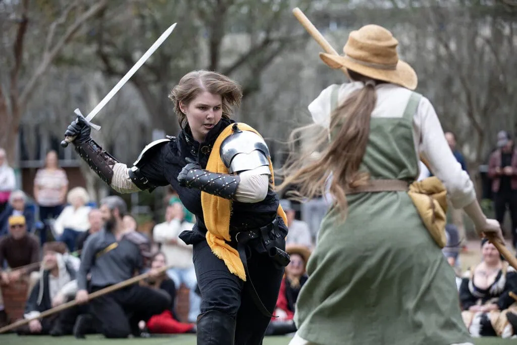 A knight armed with a sword advances on an adversary wielding a staff during a Living Chessboard game.