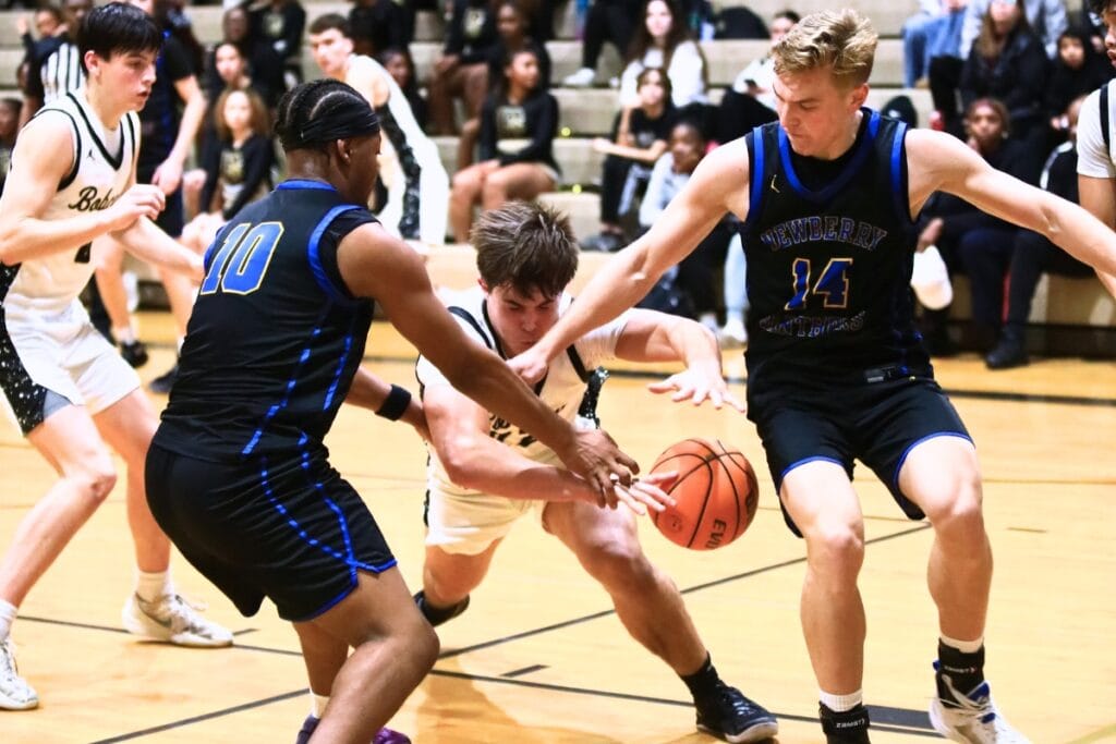 Buchholz's Evan Walker (22) dives for the ball between Newberry's Darius Debose (10) and Colton Sembower (14). Photo by C.J. Gish