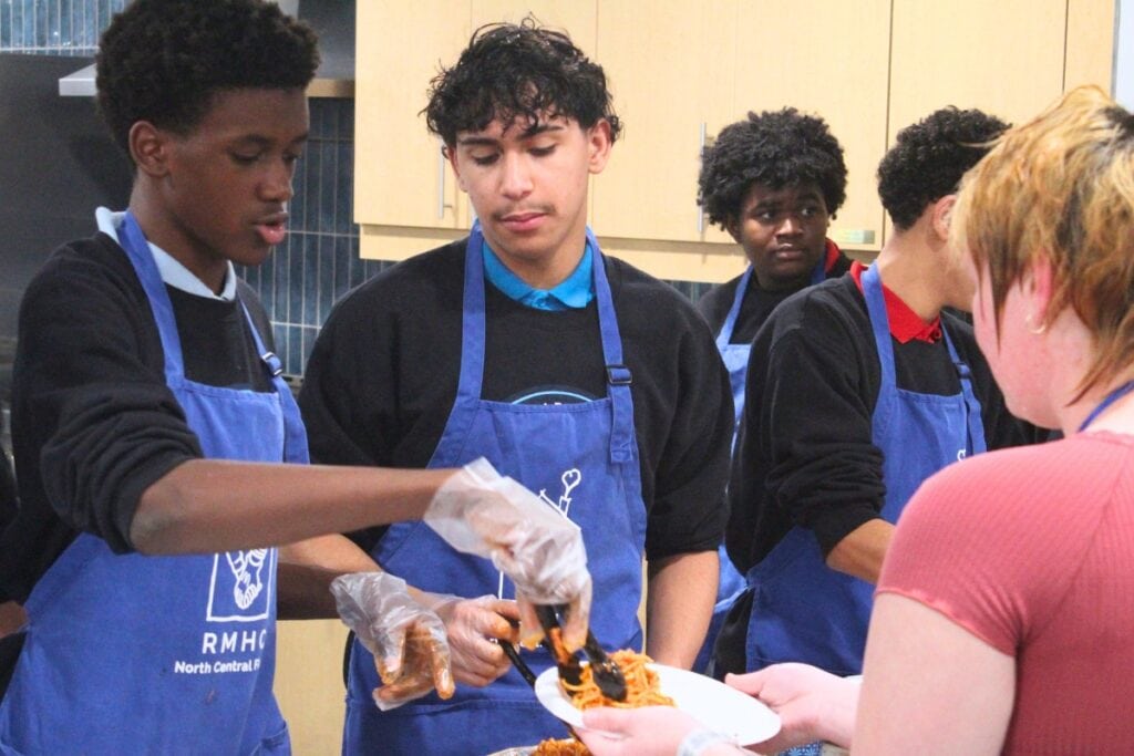Jayden Jackson (left) places a scoop of spaghetti and meatballs onto a resident's plate on Wednesday night. Photo by Nick Anschultz