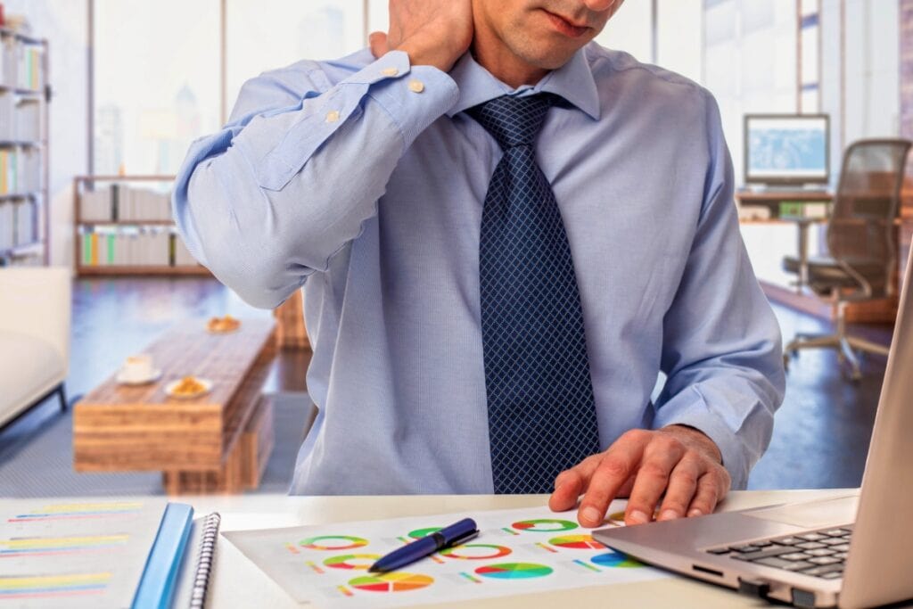 Man working at computer rubbing neck. Metro Creative