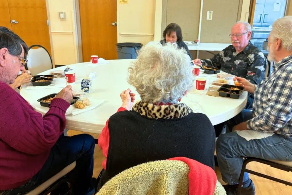 A table of older adults enjoying lunch at the senior center. Photo by Ronnie Lovler.