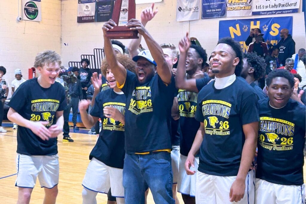 Newberry coach Patrick Green hoists the Class 3A-District 3 championship trophy after a 60-49 win over Bradford (Starke) on Saturday. Photo by Marty Pallman