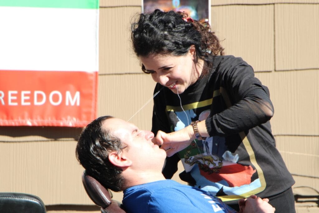 UF student Seth Haber gets his eyebrows threaded for the first time as one of 337 people who contributed to Ziba Ahmadi's (standing) world record attempt. Photo by Lillian Hamman