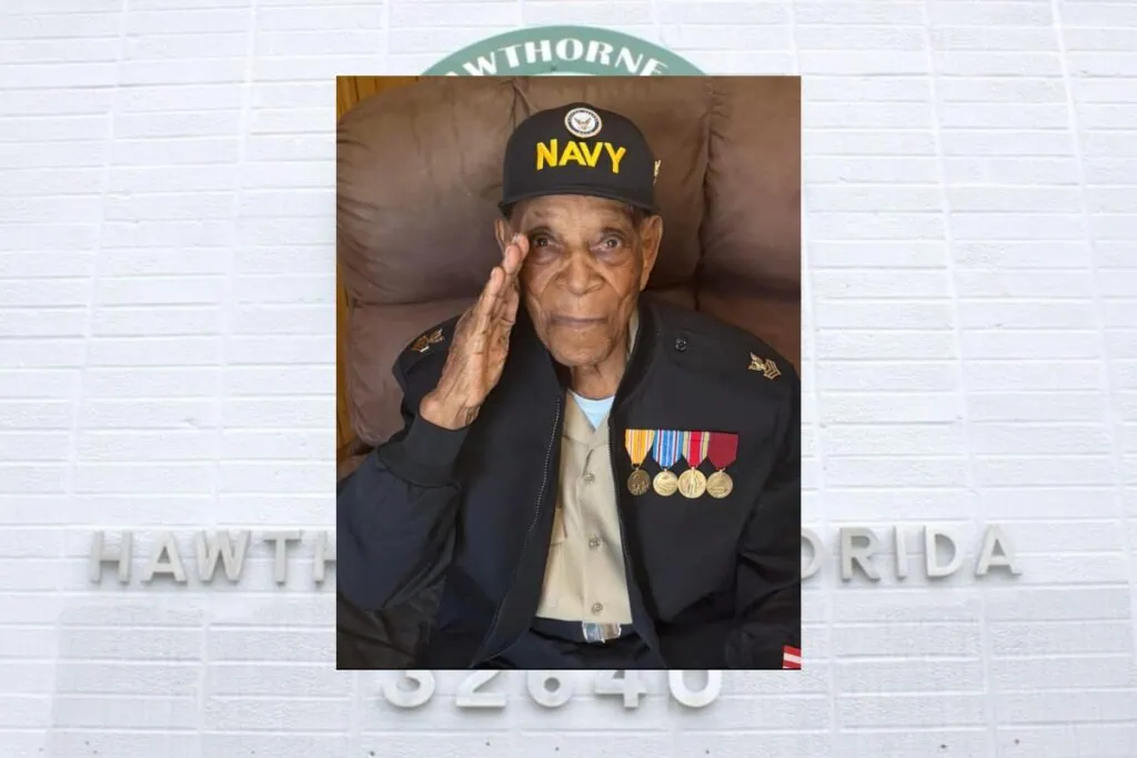 Photo of Williams saluting with medals and a Navy cap.