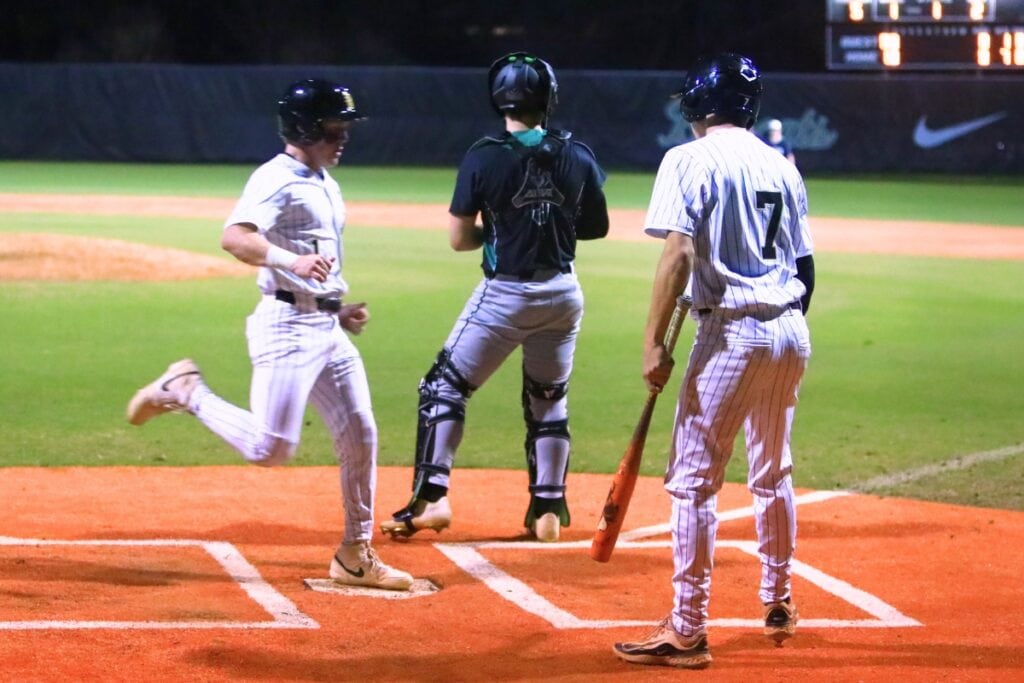 Buchholz's Hudson Sapp (1) follows Blake Brewer (7) across home plate for two more runs in a nine-run second inning against Suwannee. Photo by C.J. Gish