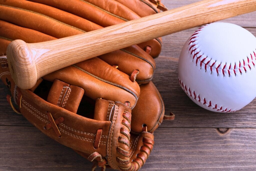 Softball, bat and glove on wood.
