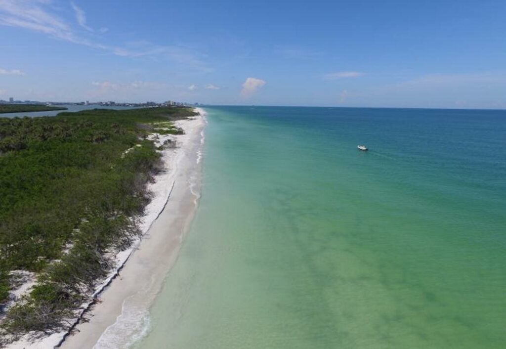 aerial shot of an island with a boat circling it