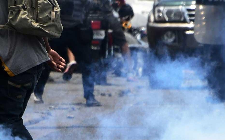 Agentes de la Policía Antidisturbios usan gas lacrimógeno para dispersar manifestantes cerca de las instalaciones de Globo Radio y TV, durante el arresto del periodista hondureño David Romero que se atrincheró durante cuatro días en su medio para evitar que lo arrestaran. El hecho ocurrió en Tegucigalpa el 28 de marzo de 2019.