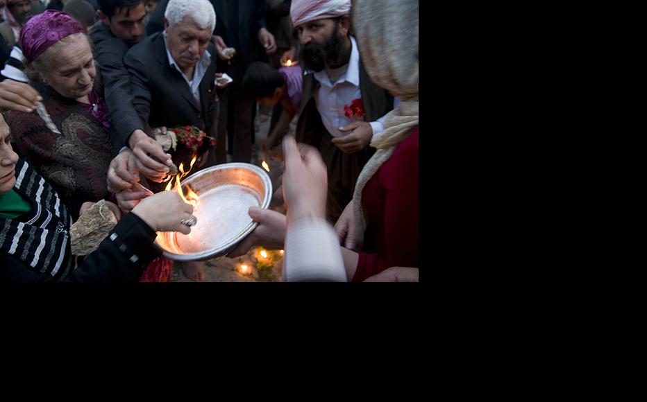 Men and women light candle wicks dipped in oil and throw them in a copper plate as part of the Yezidi New Year celebration on April 14 in Lalish Temple. Yezidi welcome the New Year by lighting candles and flames.