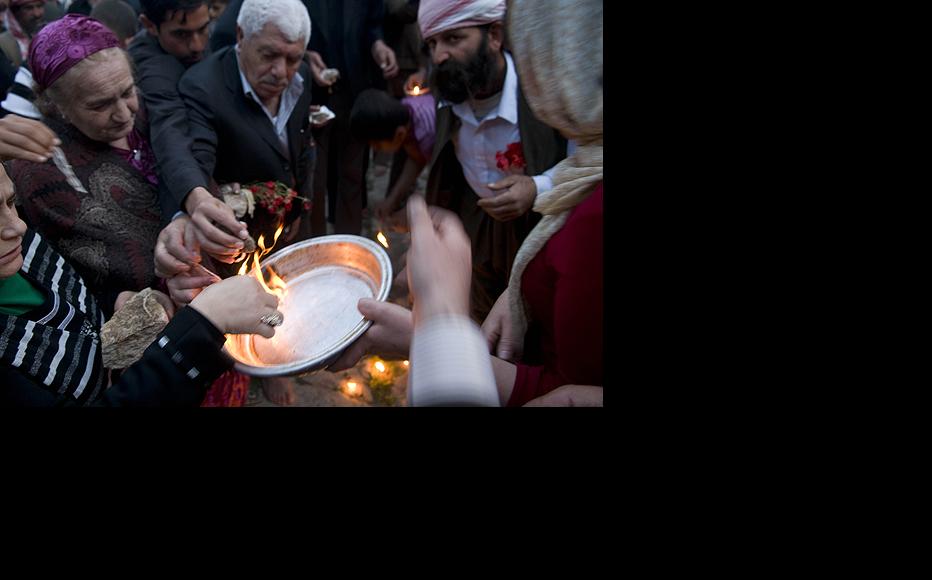 Men and women light candle wicks dipped in oil and throw them in a copper plate as part of the Yezidi New Year celebration on April 14 in Lalish Temple. Yezidi welcome the New Year by lighting candles and flames. 