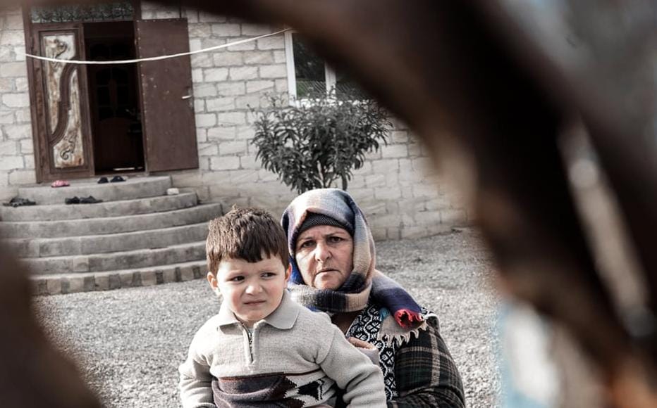 Shahla Gasimova with her young grandson. Artillery fire hit their home, leaving holes in their front door.