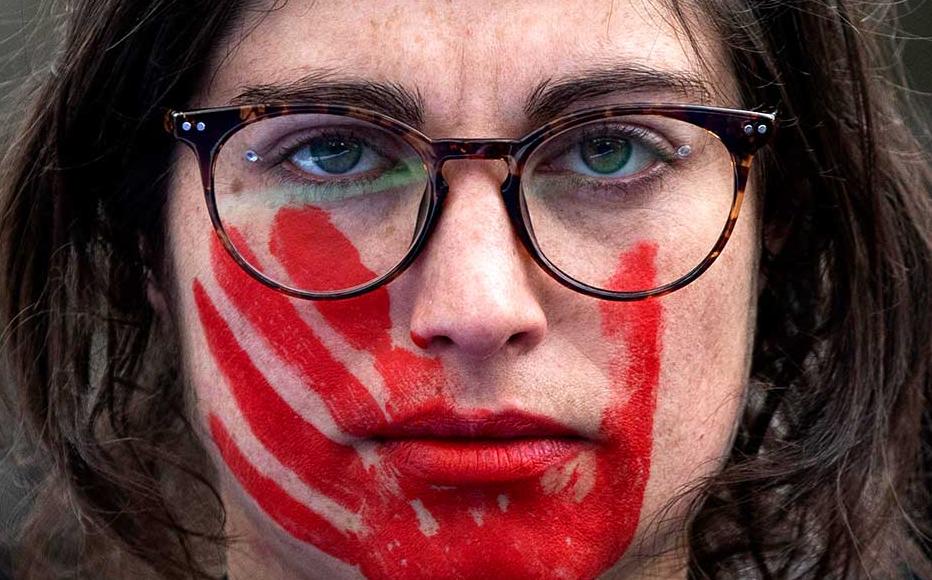 A woman wears red face paint depicting a hand during a protest during the International Women's Day in Madrid, Spain.