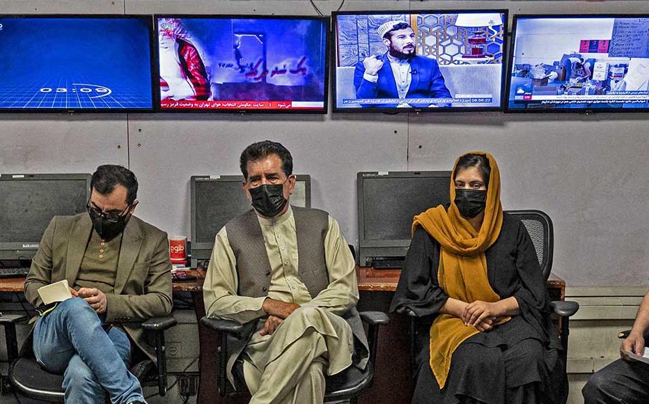 Reporters for Tolo News cover their faces as they attend an editorial meeting at Tolo TV station in Kabul on May 22, 2022.