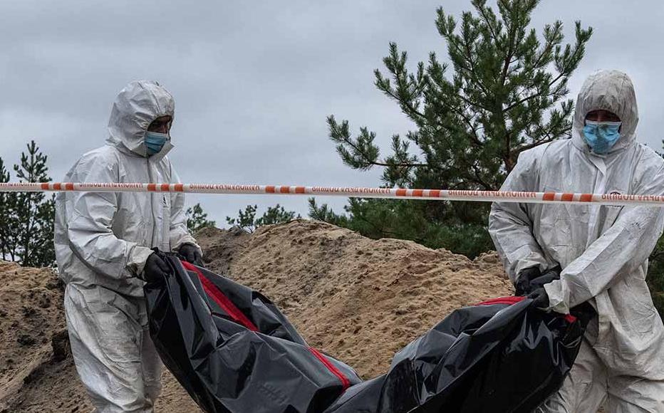 Forensic investigators remove an exhumed body from what is believed to be a mass grave on October 11, 2022 in Lyman, Donetsk oblast, Ukraine.