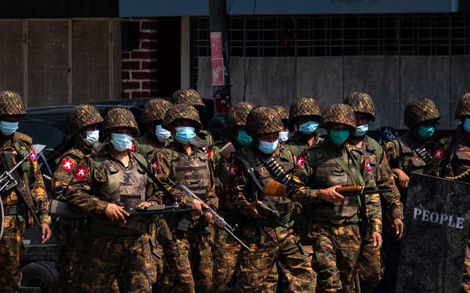 Military soldiers walk down a street while carrying weapons that contain live ammunition after clashes with protesters on March 03, 2021 in Yangon, Myanmar.