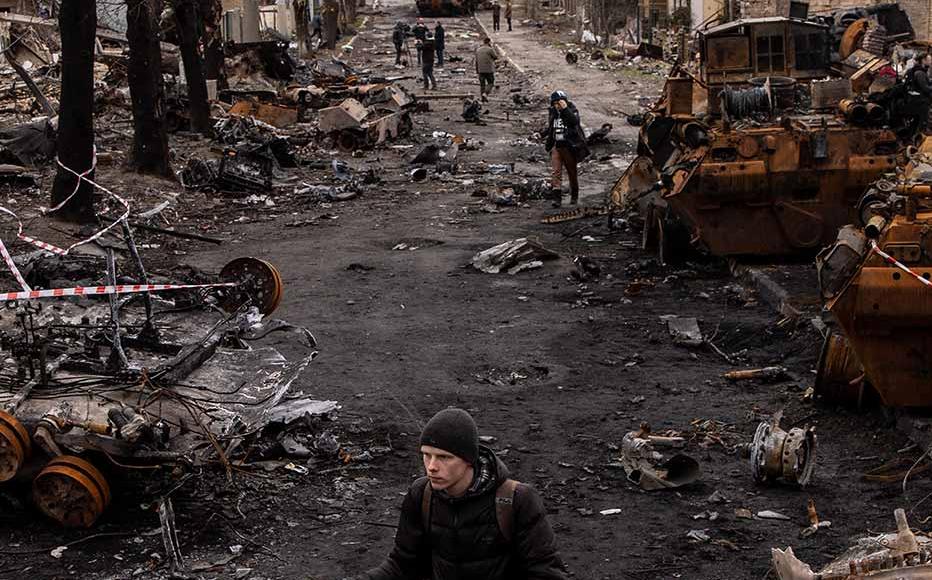 A man pushes his bike through debris and destroyed Russian military vehicles on a street on April 06, 2022 in Bucha, Ukraine. The Ukrainian government has accused Russian forces of committing a "deliberate massacre" as they occupied and eventually retreated from Bucha, 25km northwest of Kyiv. Hundreds of bodies have been found in the days since Ukrainian forces regained control of the town.