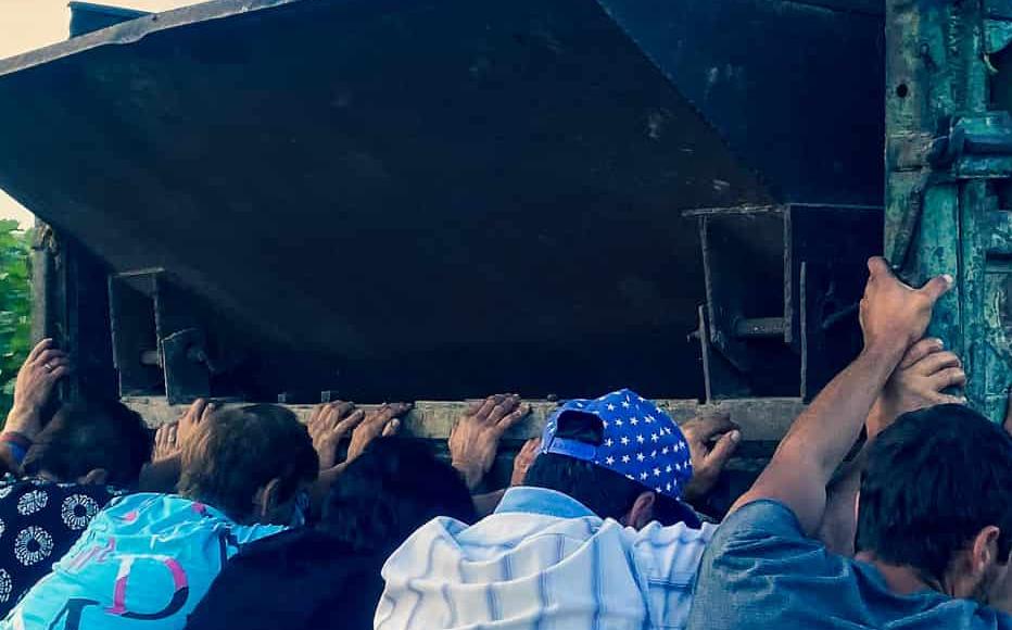 Workers join forces to push the truck where grapes are unloaded from the buckets. Workers join forces to push the truck where grapes are unloaded from the buckets.