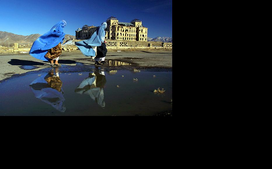 Women in burqas walk in front of the ruins of Darulaman Palace in Kabul. (Photo: Paula Bronstein/Getty Images)