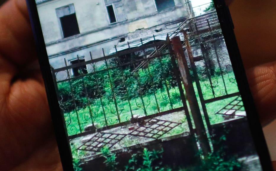 Irma Nachkebia, 52, displays her abandoned house in Abkhazia on her phone. The photo was sent to her by acquaintances. 