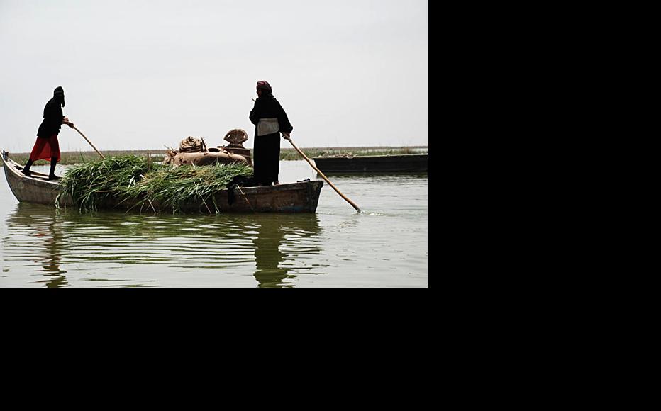 Ma'dan boatsmen guide their slender wooden boat past a submerged Iraqi army tank in the Hor Saleel marshland area in Iraq's southern Basra province. (Photo: Ali Abu Iraq)