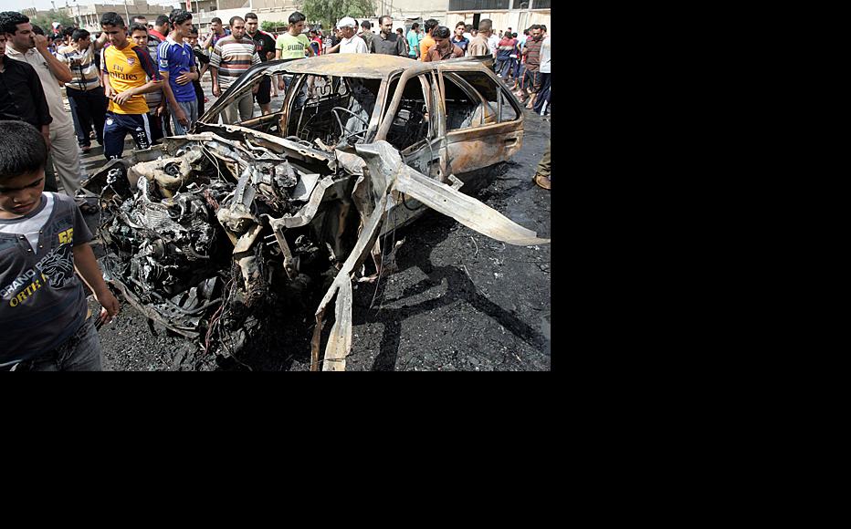 Residents of the sprawling Baghdad slum of Sadr City examine the burned out remains of a car on April 23, hours after the vehicle was used by insurgents to attack a nearby Shia mosque. (Photo: Serwan Azez/Metrography)