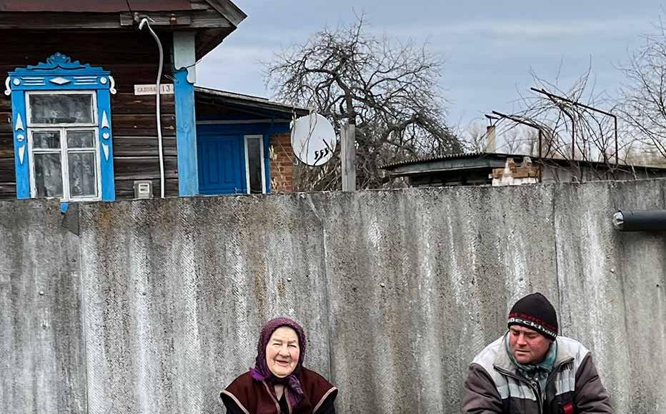 Locals sit outside a typical wooden house in Zirka.