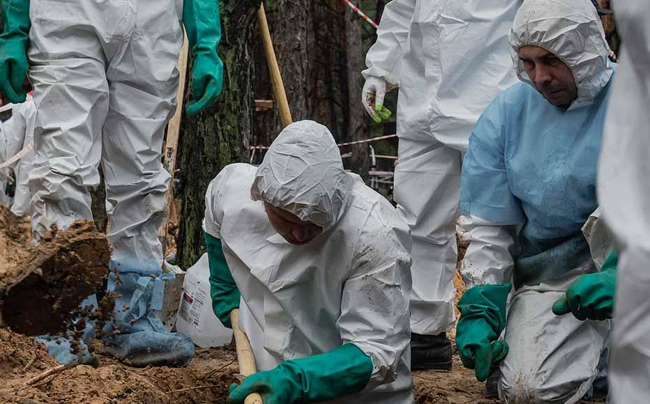 Employees of Ukraine’s state emergency service carry a body bag in the pine forest in the outskirts of the retaken town of Izyum. Ukrainian authorities discovered a mass burial site with hundreds of graves.