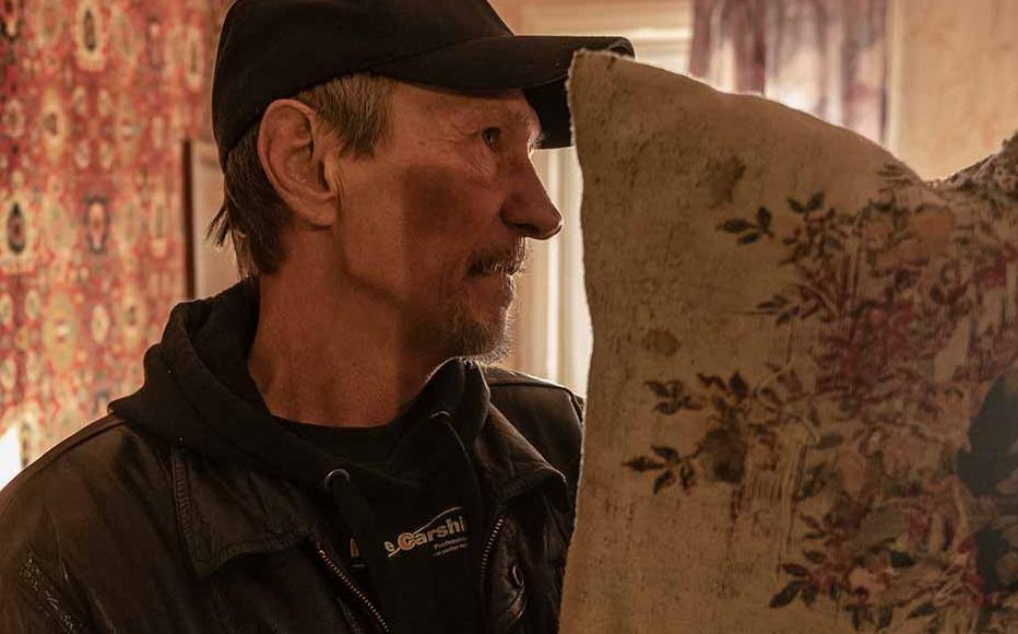 Viktor Sytnyk shows a pillow cut by shrapnel, with which he covered his face to walk into his mother’s room after a rocket fell in their yard on May 21.