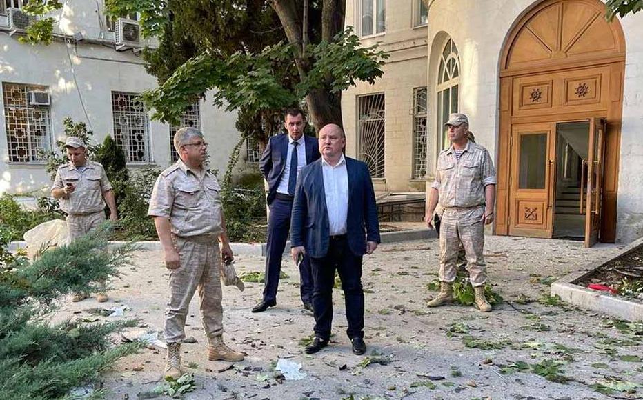 In this handout photo released by the telegram channel of Sevastopol mayor Mikhail Razvozhaev on July 31, 2022, Governor of Sevastopol Mikhail Vladimirovich Razvozhayev, center, stands at the scene of explosion at the headquarters of Russia's Black Sea Fleet in Sevastopol, Crimea.