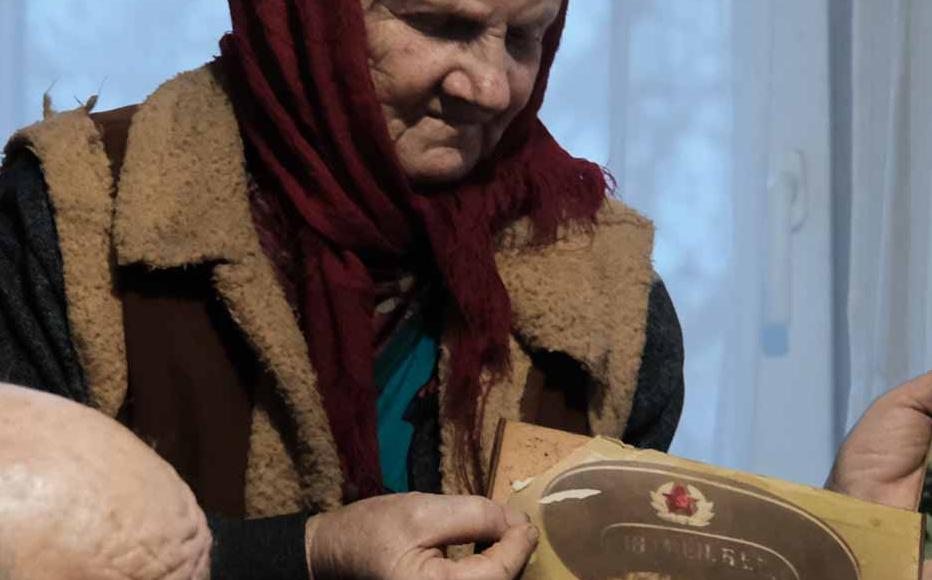 An elderly couple living in a frontline village near Bakhmut shows photos of their children.