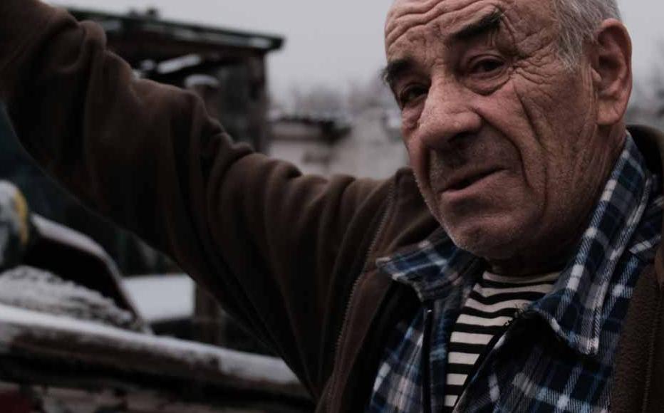 man living in a frontline village near Bakhmut, in Donetsk region, indicates where an artillery shell hit his yard, destroyed the kitchen and crushing his car.