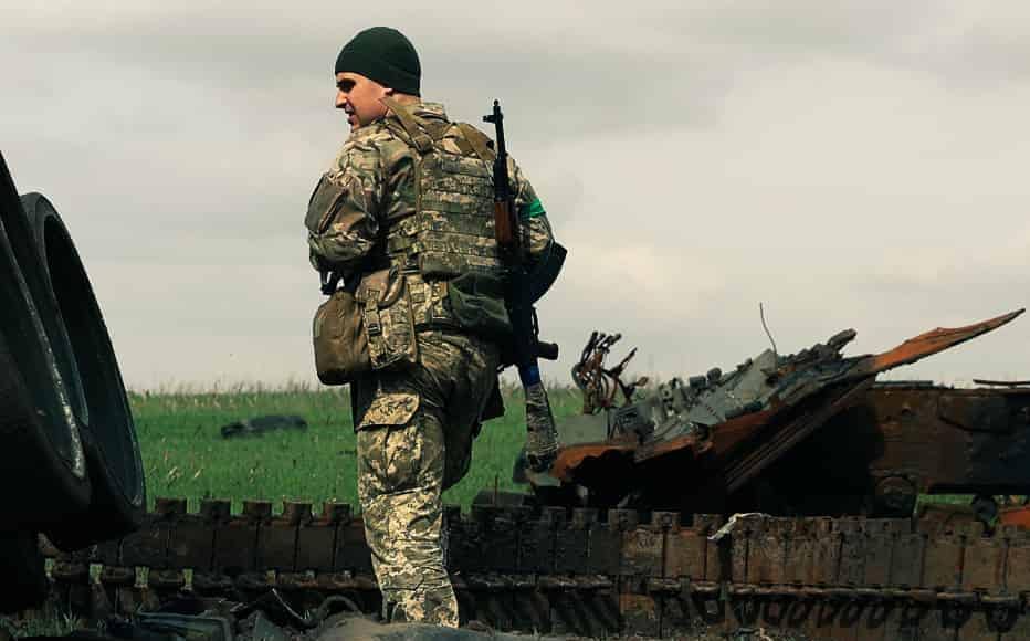 A Ukrainian soldier walks near a destroyed Russian tank in the village of Gusarovka, in Kharkiv region.