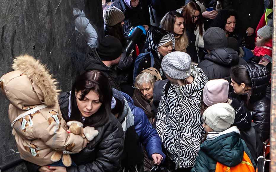 The staircase leading up to the platforms forms a chokepoint due to the sheer volume of people and their luggage.