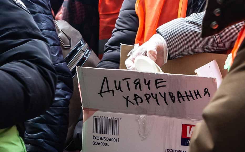 Volunteers distribute baby food on the platform where hundreds await the train heading to Poland.