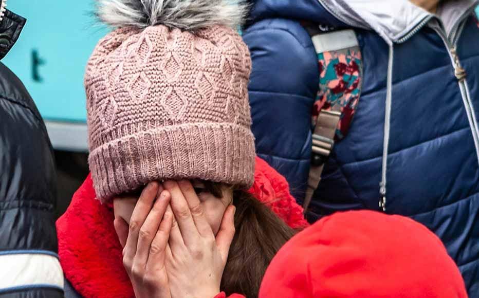 A child cries as her family is about to board the train, leaving the father behind.