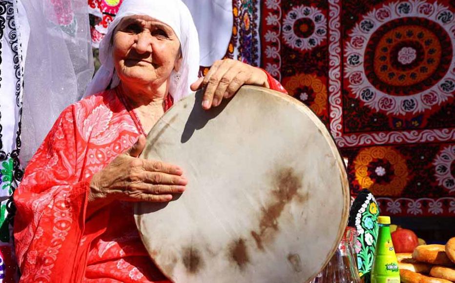  A Tajik woman in traditional clothes plays the daf, or doira, a tambourine-like instrument with jingles, played across Central Asia.