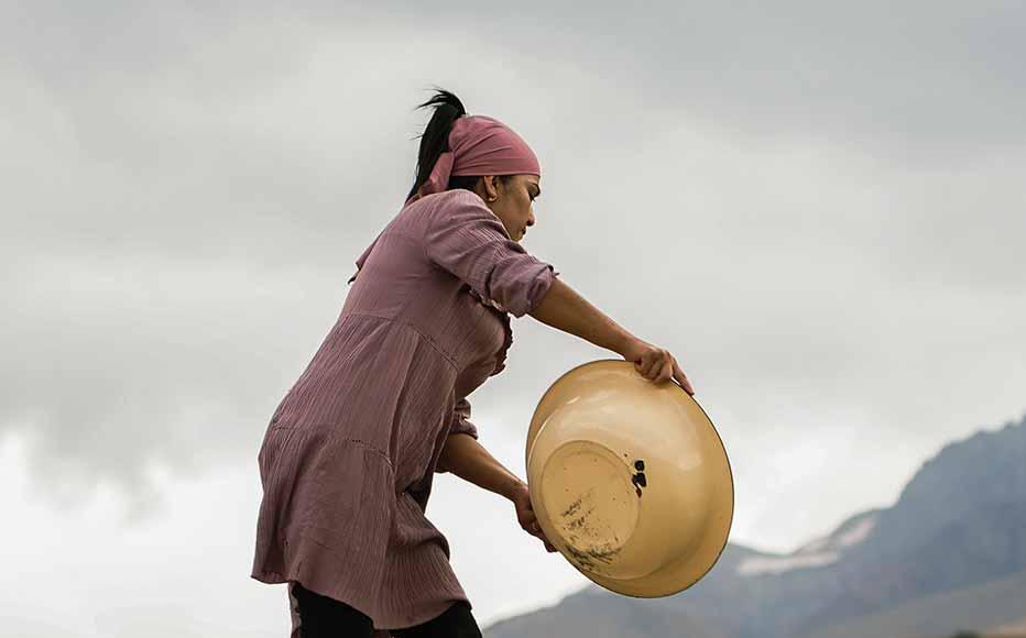 A woman pours grain on the roof. Some of the village’s oldest houses have an earthen roof and residents use the surface to dry fruit and grain.