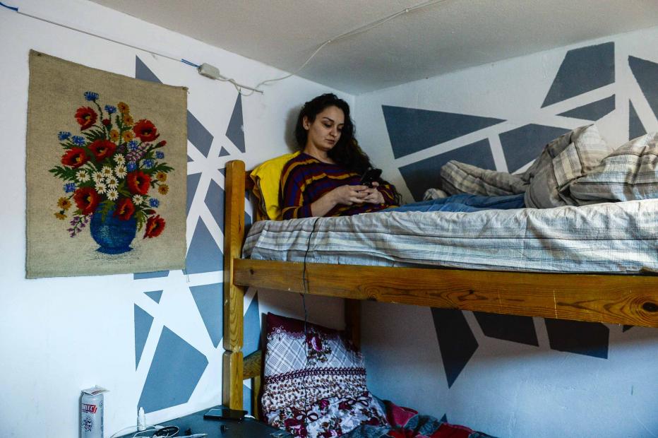 A Georgian woman checks her phone inside a flat she shares with fellow migrant workers.